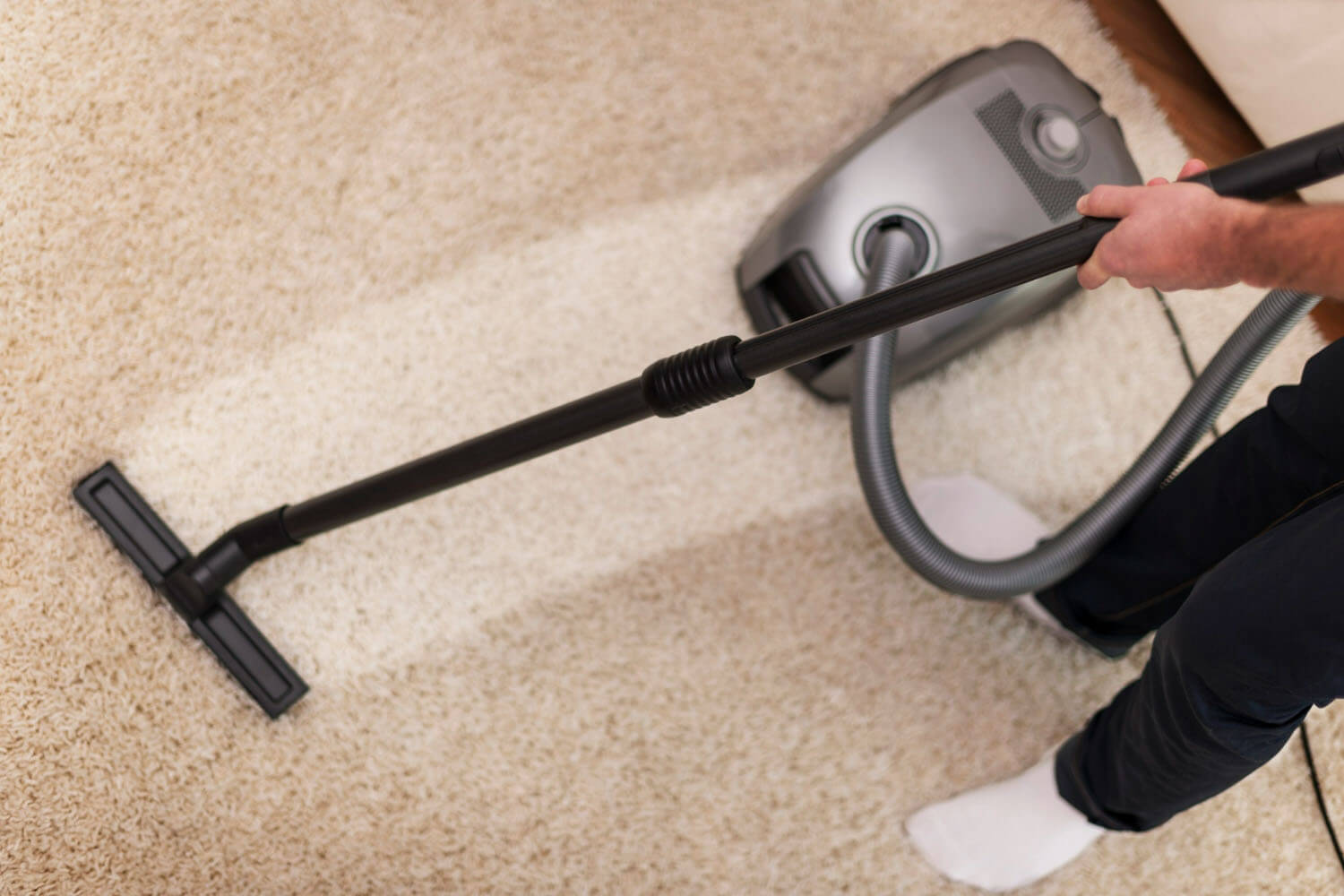 housekeeper is vacuuming the dirty carpet
