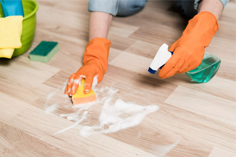 housekeeper wearing orange gloves cleaning the floor