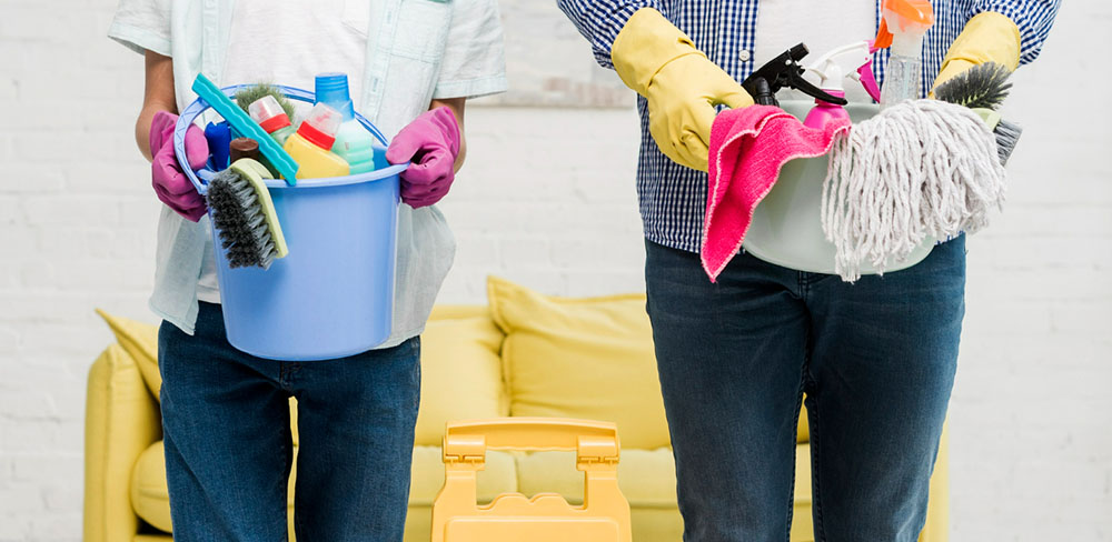 Two cleaners holding buckets filled with cleaning tools